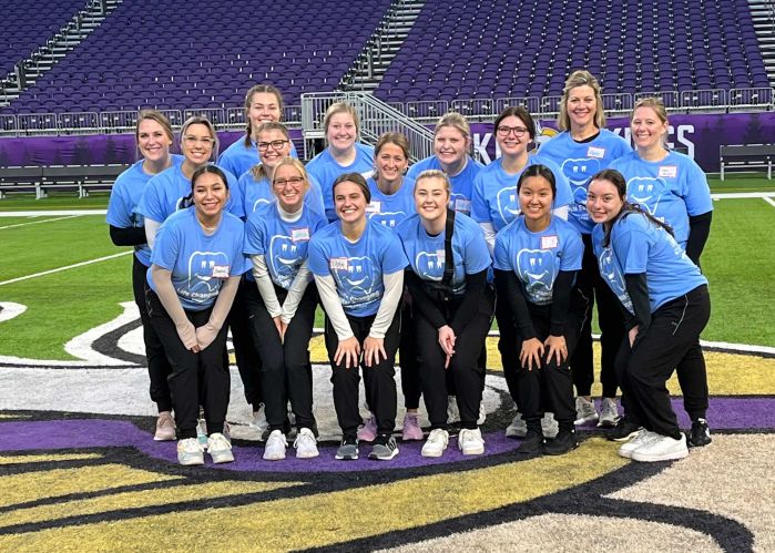 Dental Hygiene students in group on football field, smiling at camera