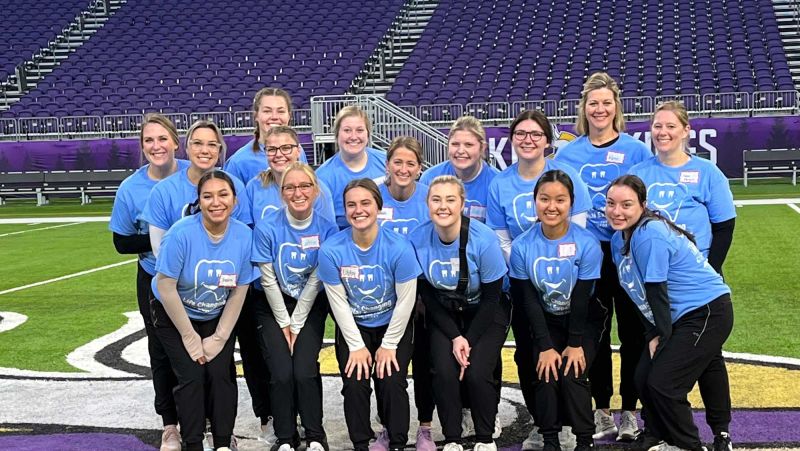 Dental Hygiene students in group on football field, smiling at camera