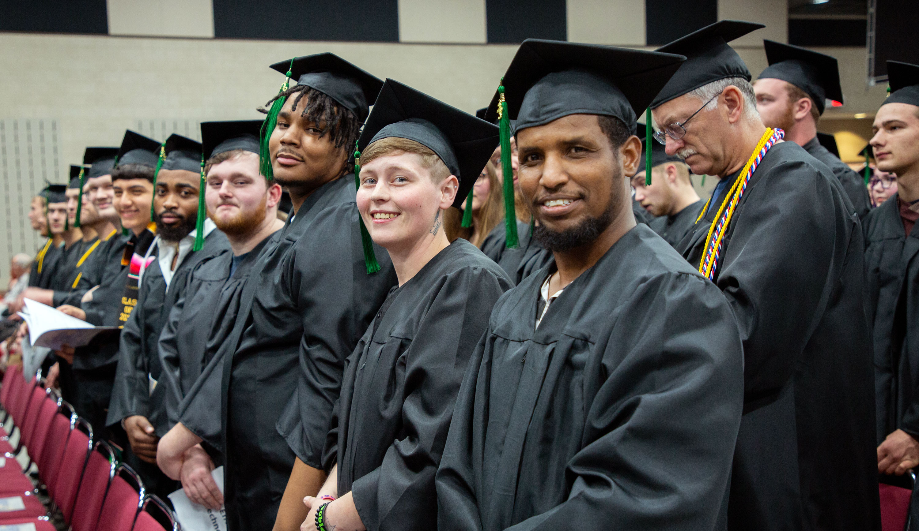 Graduates in regalia smiling at camera