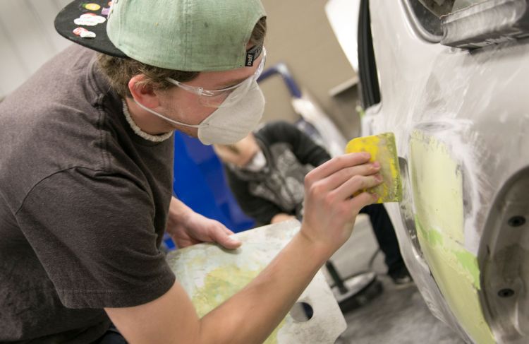 Man working on patching a car's body