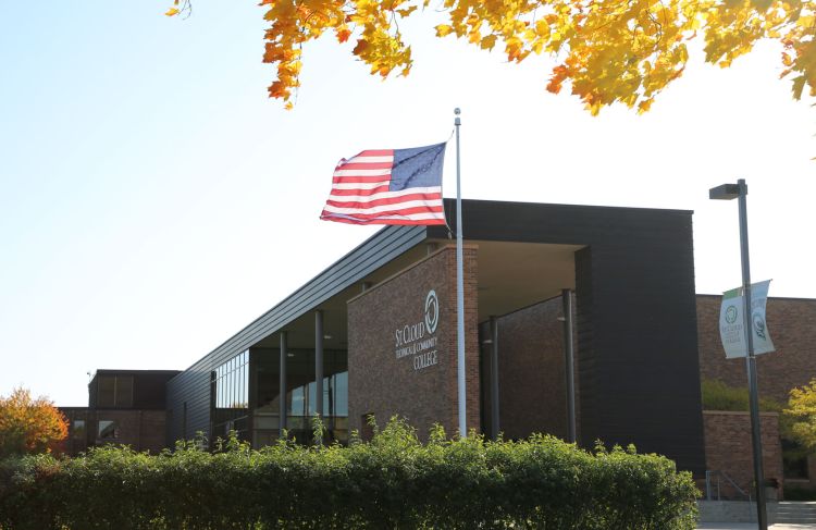 SCTCC main entrance with flag blowing in wind and yellow leaves at edge of image