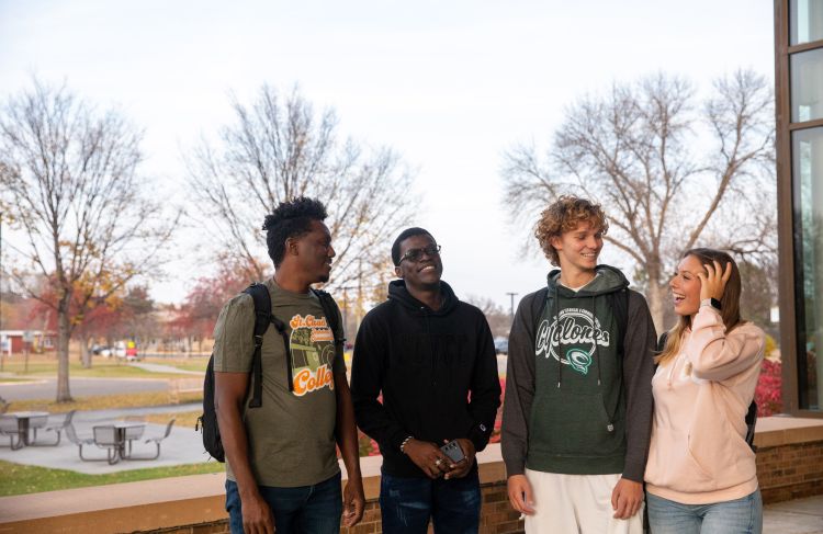 group of 4 international students outside door one, laughing in conversation
