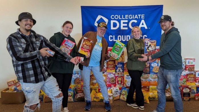 DECA officers, donated cereal smile at camera. names left to right at end of story.