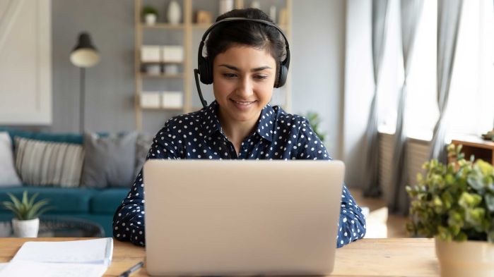 Woman with headset working on laptop at home