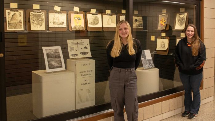 Allison and Samara standing in front of artwork display case