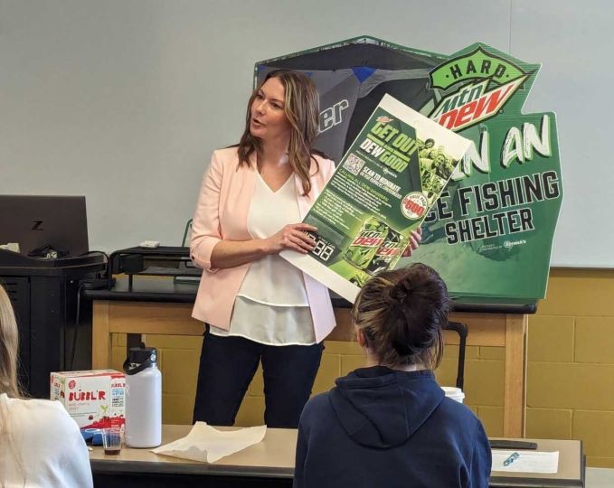 Eve Miller holds poster in front of classroom