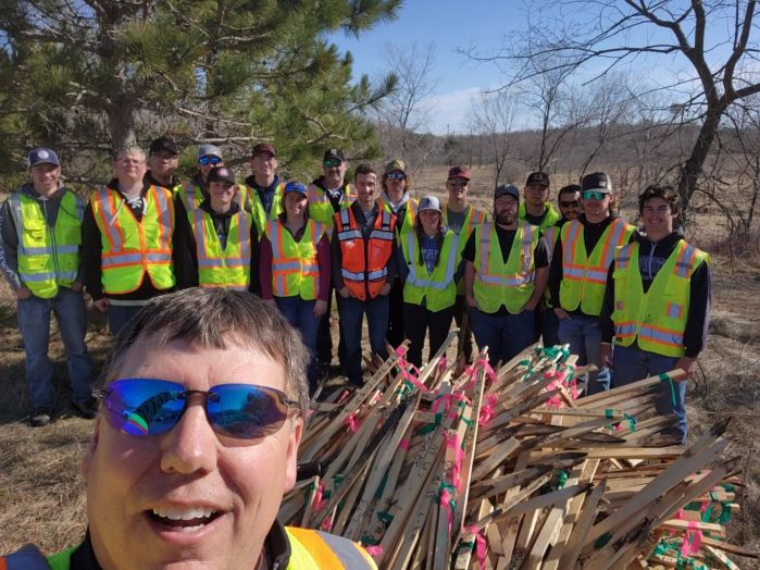 Group of students in yellow safety vests and instructor taking selfie