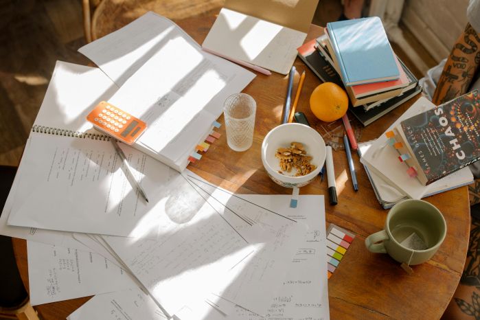 desk full of study supplies. Paper, snacks, books, & computer