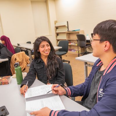 students sitting at a desk in a classroom talking