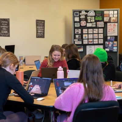 students in classroom, working on computers with designs in background