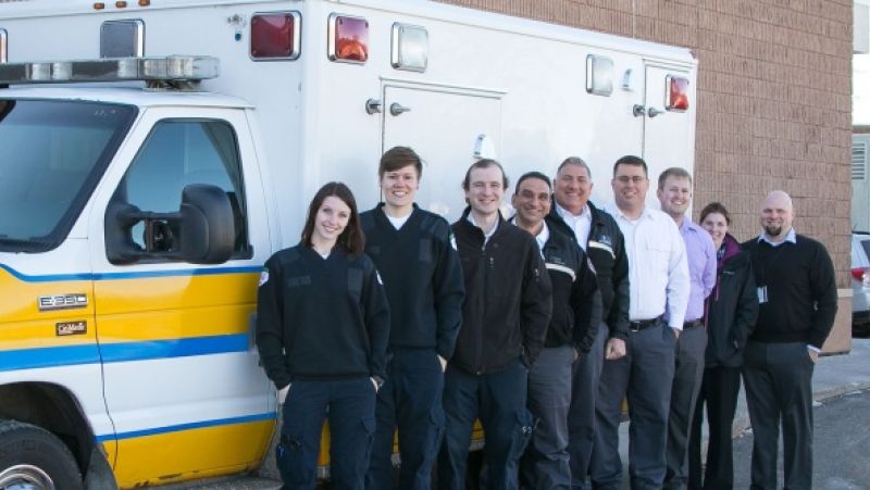 group of paramedicine student standing in front of white and yellow ambulance