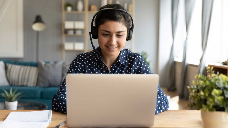 Woman with headset working on laptop at home