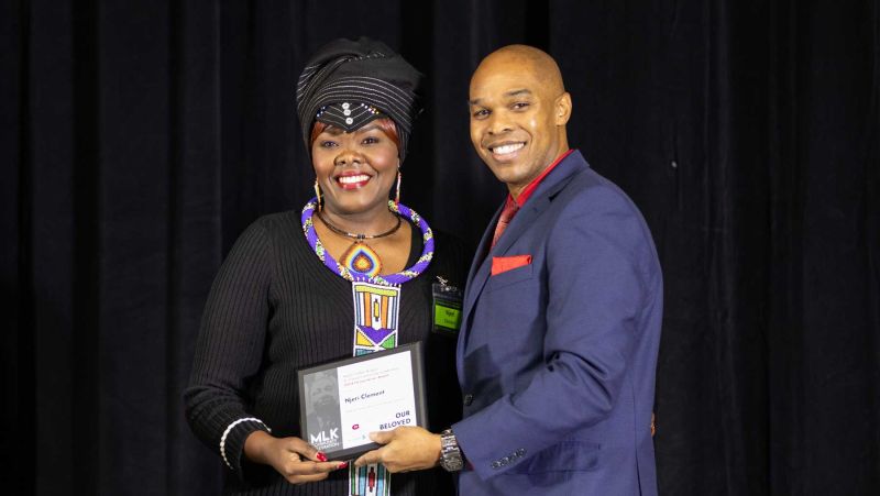 Njeri and Jason Woods with her award smiling at camera