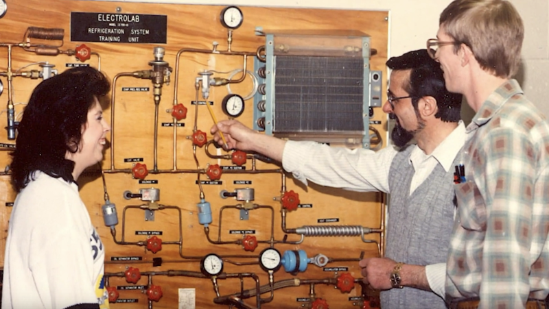 two students and instructor looking at electrical work