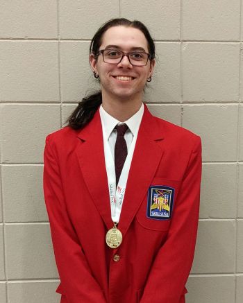 LJ Olson with medal, smiling at camera