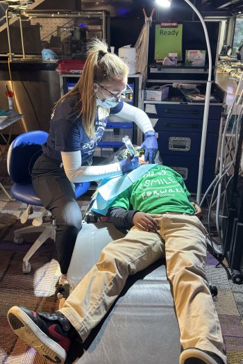 student working on a kid with dental tools.