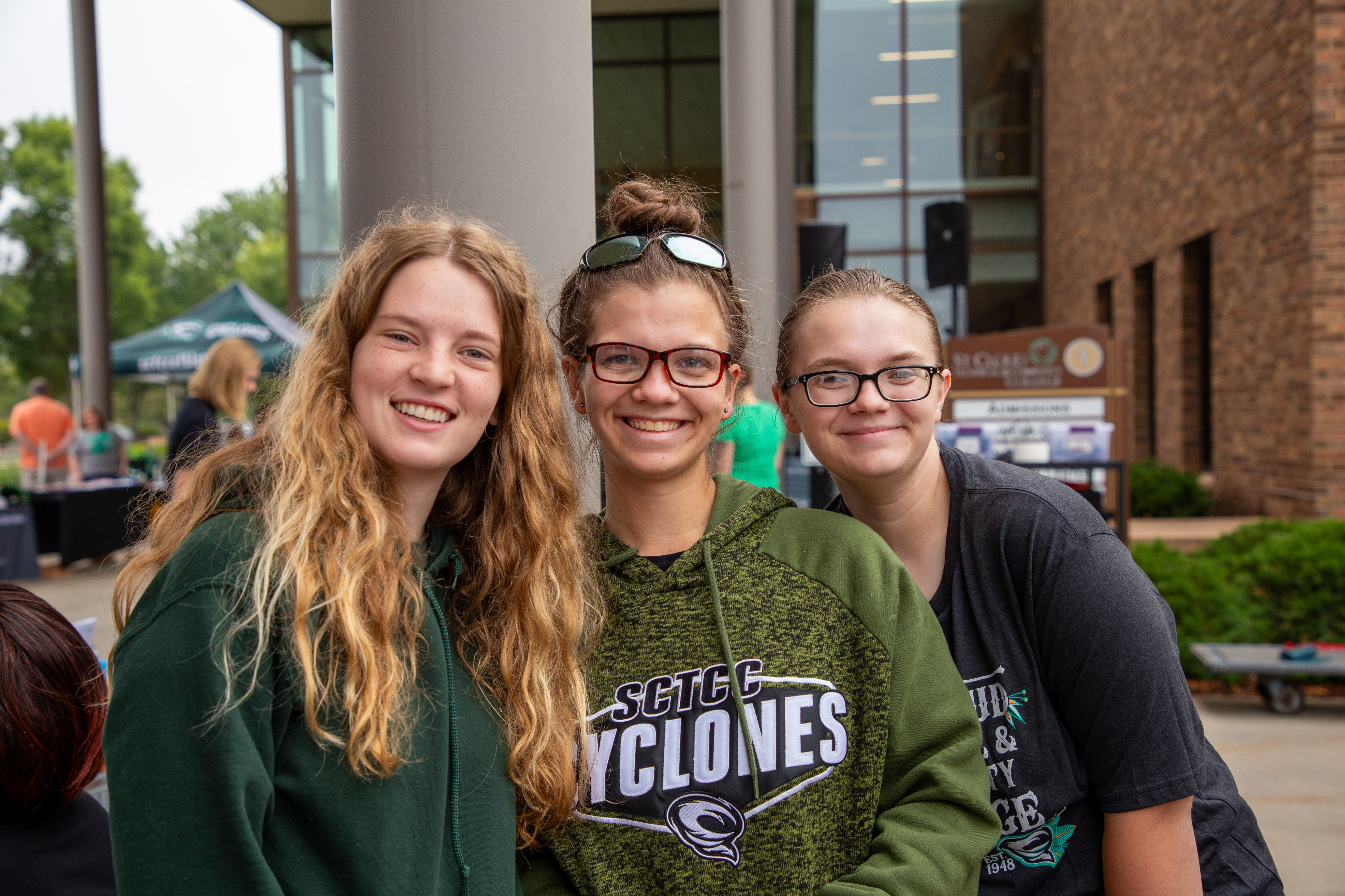 three women in green shirts smile at camera